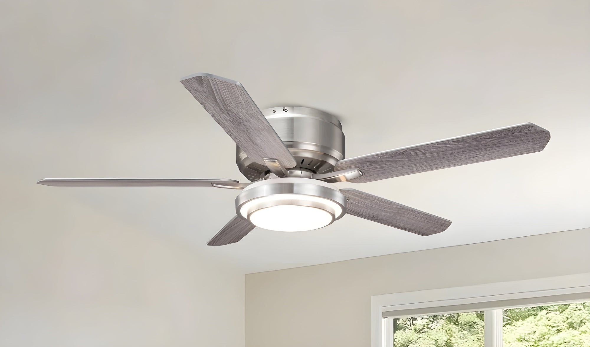 Modern ceiling fan with brushed nickel finish and integrated LED light in a bright room