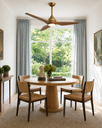 Modern wooden ceiling fan with integrated light fixture in a bright dining room.