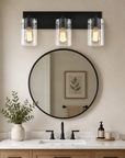 Modern 3-light bathroom vanity fixture with clear glass shades above a round mirror